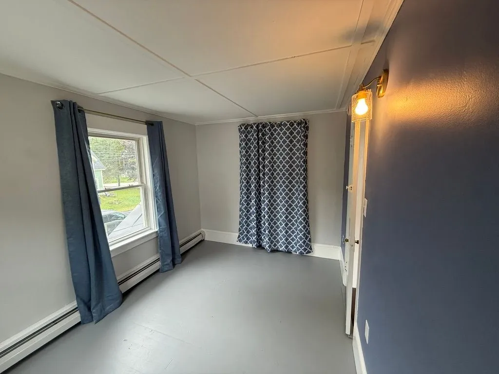Recently renovated bedroom with gray walls, a window, patterned curtains, and gray flooring at 40 Russell Street
