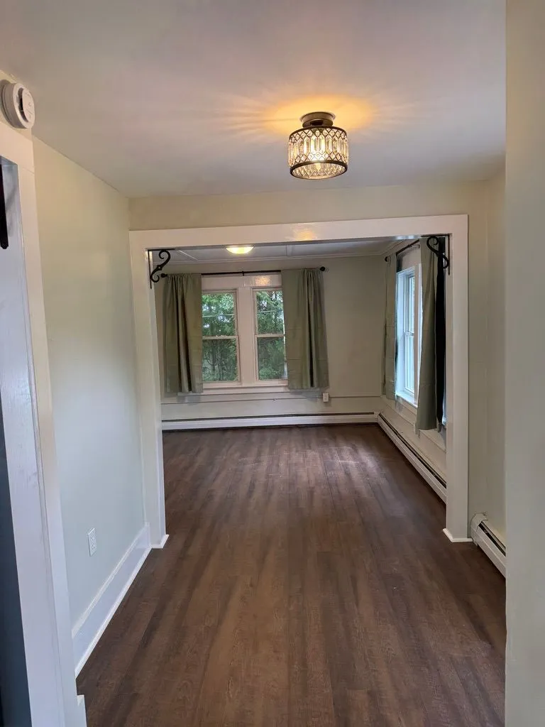 Recently renovated living area with wood-look flooring, a large window, and warm ceiling light at 40 Russell Street