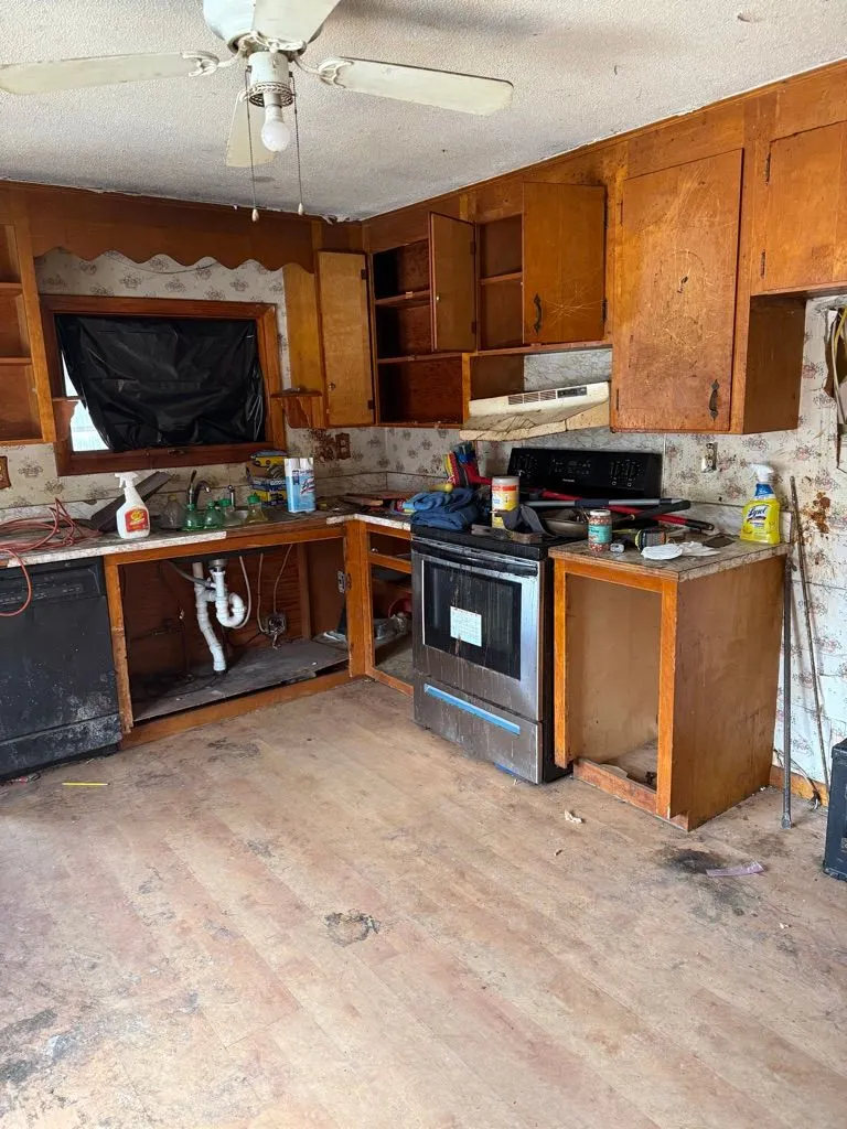Distressed kitchen before renovation with dated cabinets and unfinished surfaces