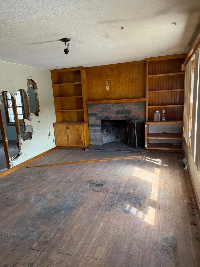 Distressed living room before renovation with damaged walls and worn flooring